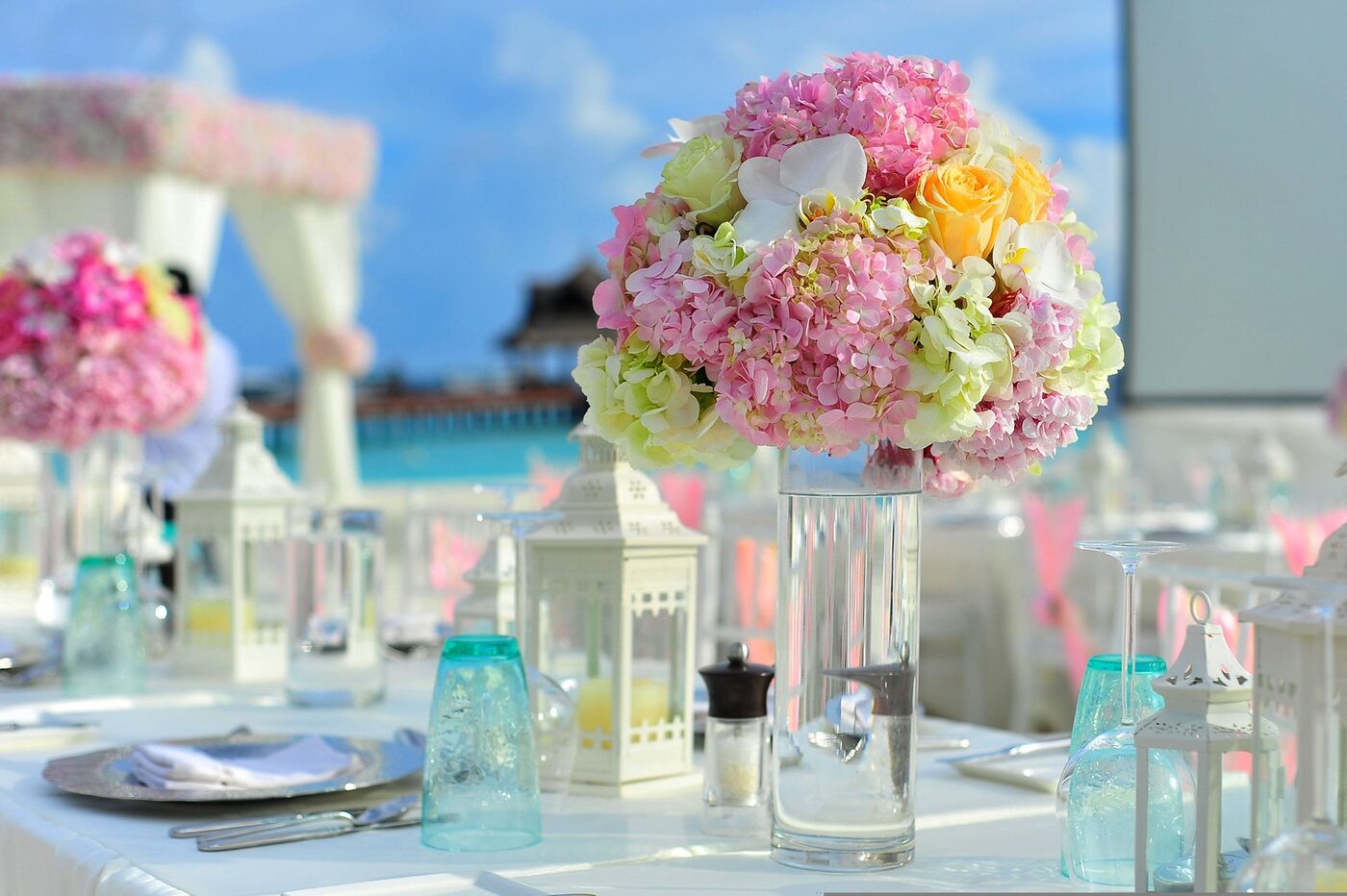 Üppiges Blumenarrangement aus rosa Hortensien, Rosen und Orchideen als Tischdekoration bei einer Feier am Meer