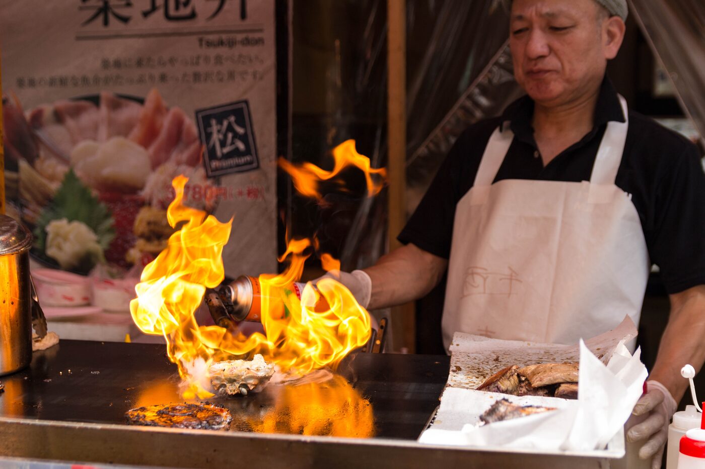 Koch flambiert ein Gericht auf dem Grill mit hoher Stichflamme, Live-Cooking-Station